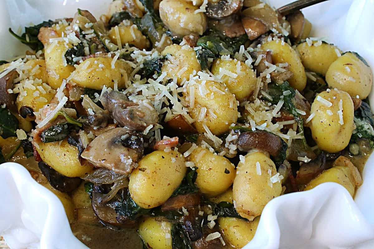 Potato Gnocchi with Spinach and Mushrooms in a white bowl.