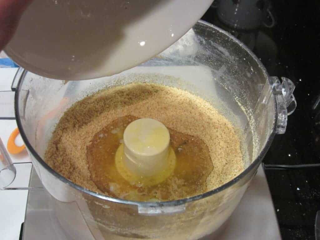 Melted butter being added to graham cracker crumbs.