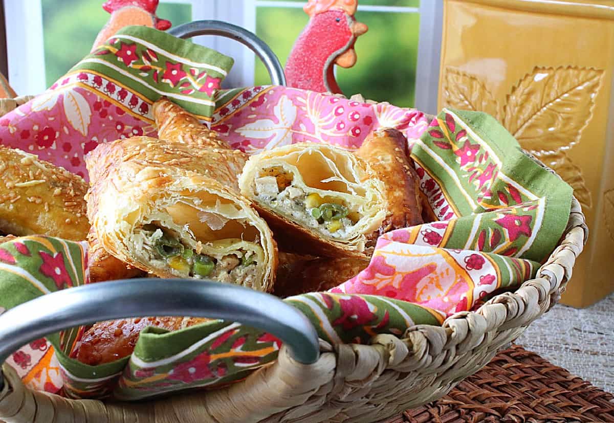 A basket with a colorful napkin and filled with Chicken Pot Pie Turnovers.