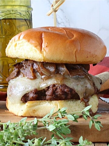 A delicious looking Mushroom Swiss Burger with melted cheese and caramelized onions and fresh thyme.