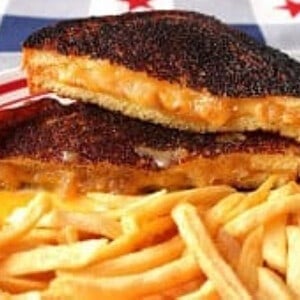 A sliced Brie and Cheddar Grilled Cheese Sandwich with a pile of French fries.