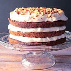 A pretty Chocolate Hazelnut Cake with Whipped Cream on a glass cake stand.