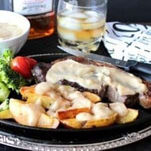 A fancy dinner plate filled with Steak and Roasted Potatoes and Bourbon Butter Sauce.