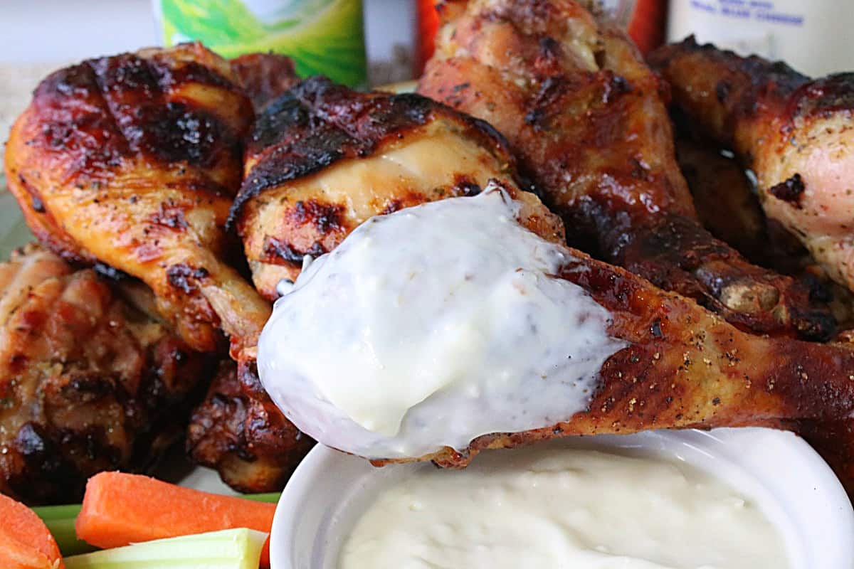 Closeup of a chicken leg that's been dipped into blue cheese dipping sauce.