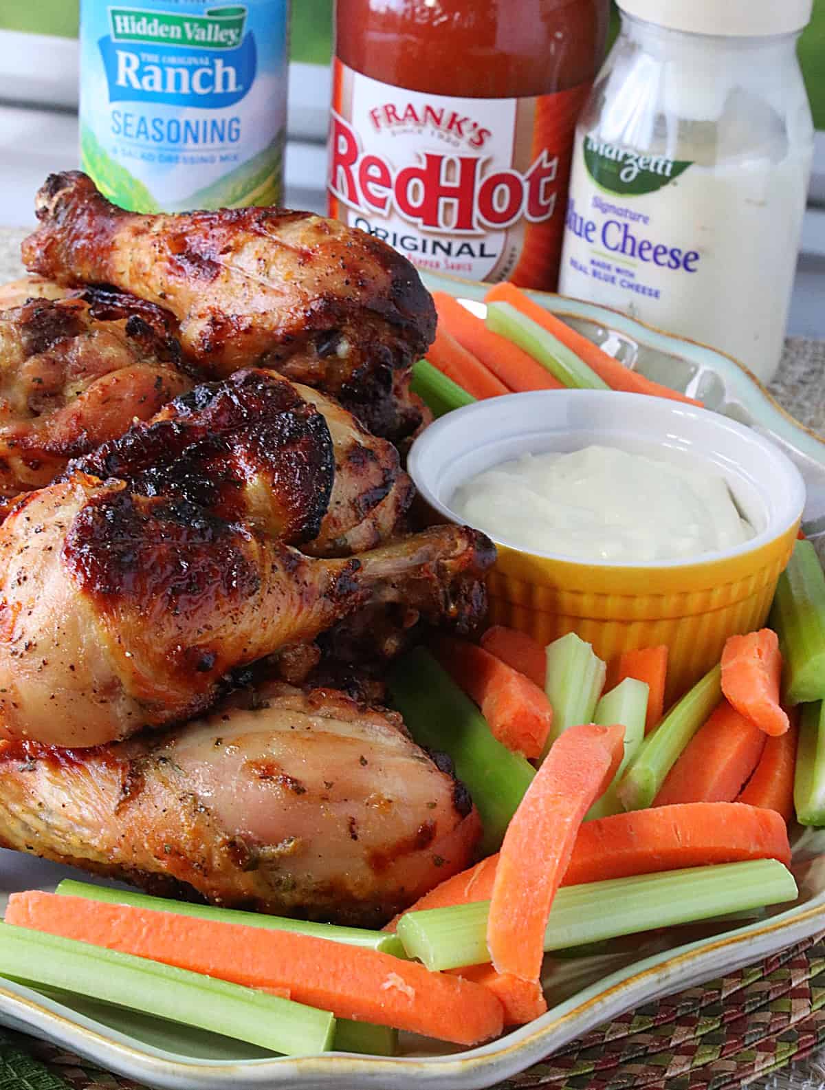 Delicious looking air fryer chicken legs surrounded by carrots and celery on a platter.