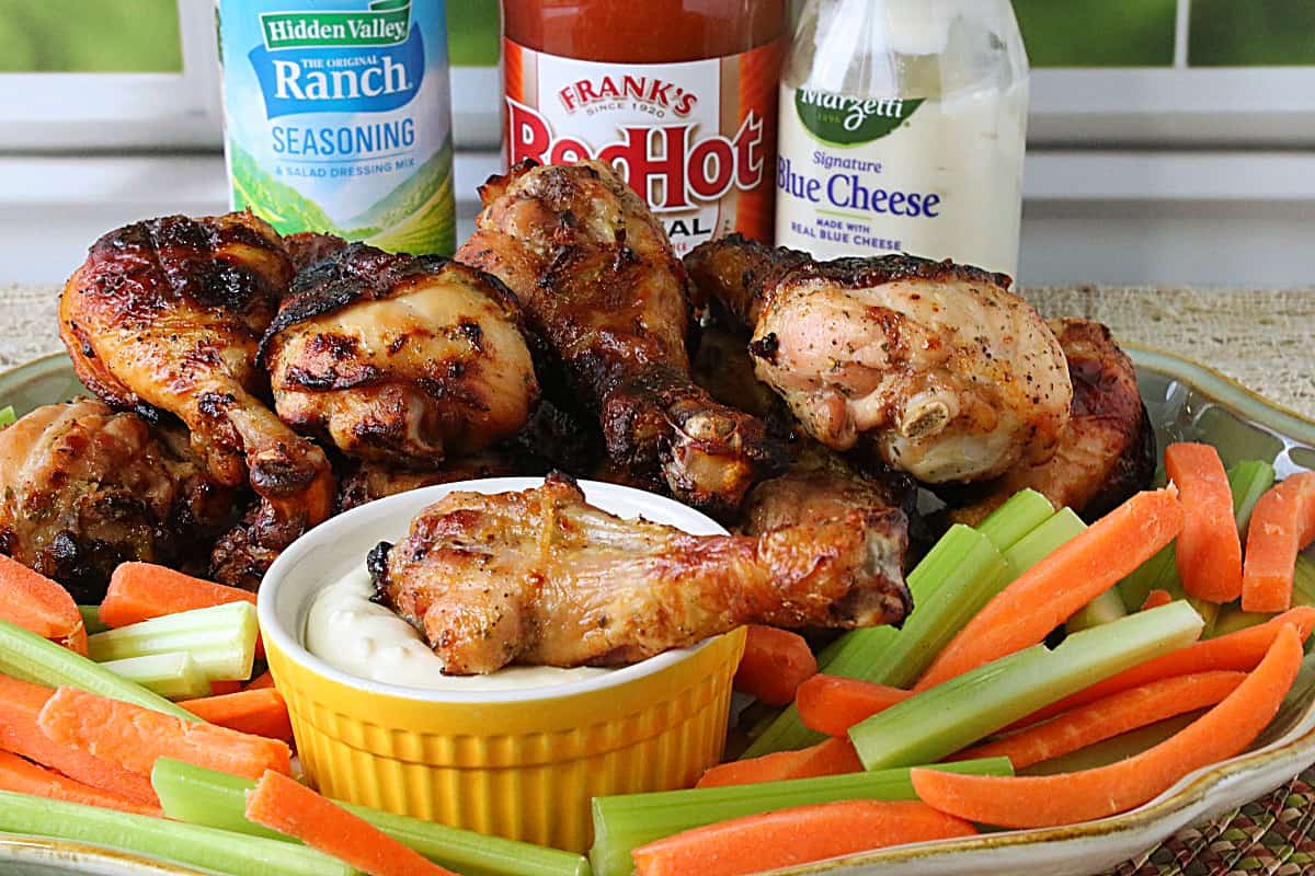 A pile of Buffalo Ranch Chicken Legs on a platter surrounded by carrot and celery sticks.