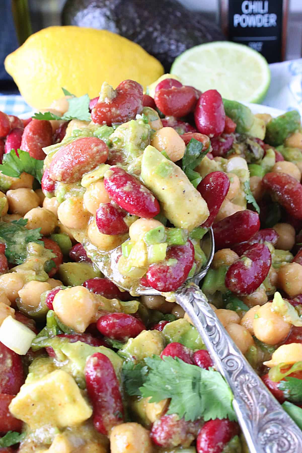 A pretty silver serving spoon with a serving of Avocado and Kidney Bean Salad on it.