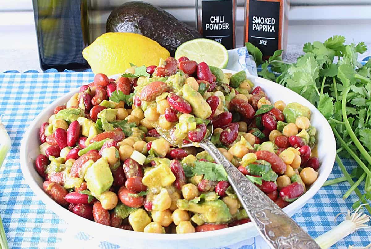 A bright and colorful bowlful of Avocado and Kidney Bean Salad along with a serving spoon.