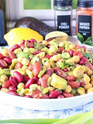 A vibrant bowl of Avocado and Kidney Bean Salad with a serving spoon.
