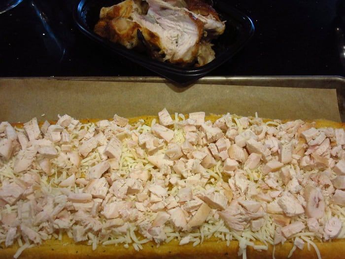 Chopped rotisserie chicken on top of a garlic bread pizza.