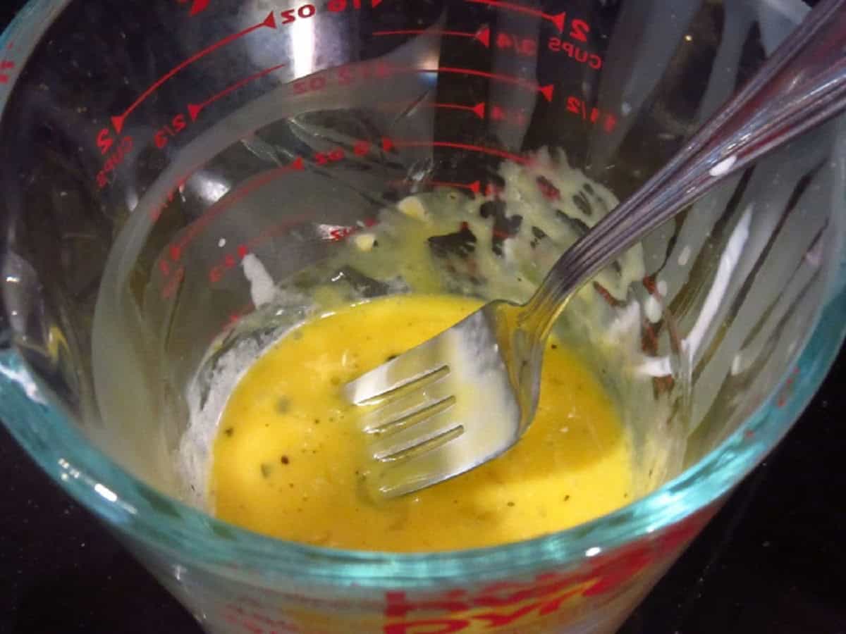 Tempering eggs in a glass measuring cup for making Alfredo sauce.