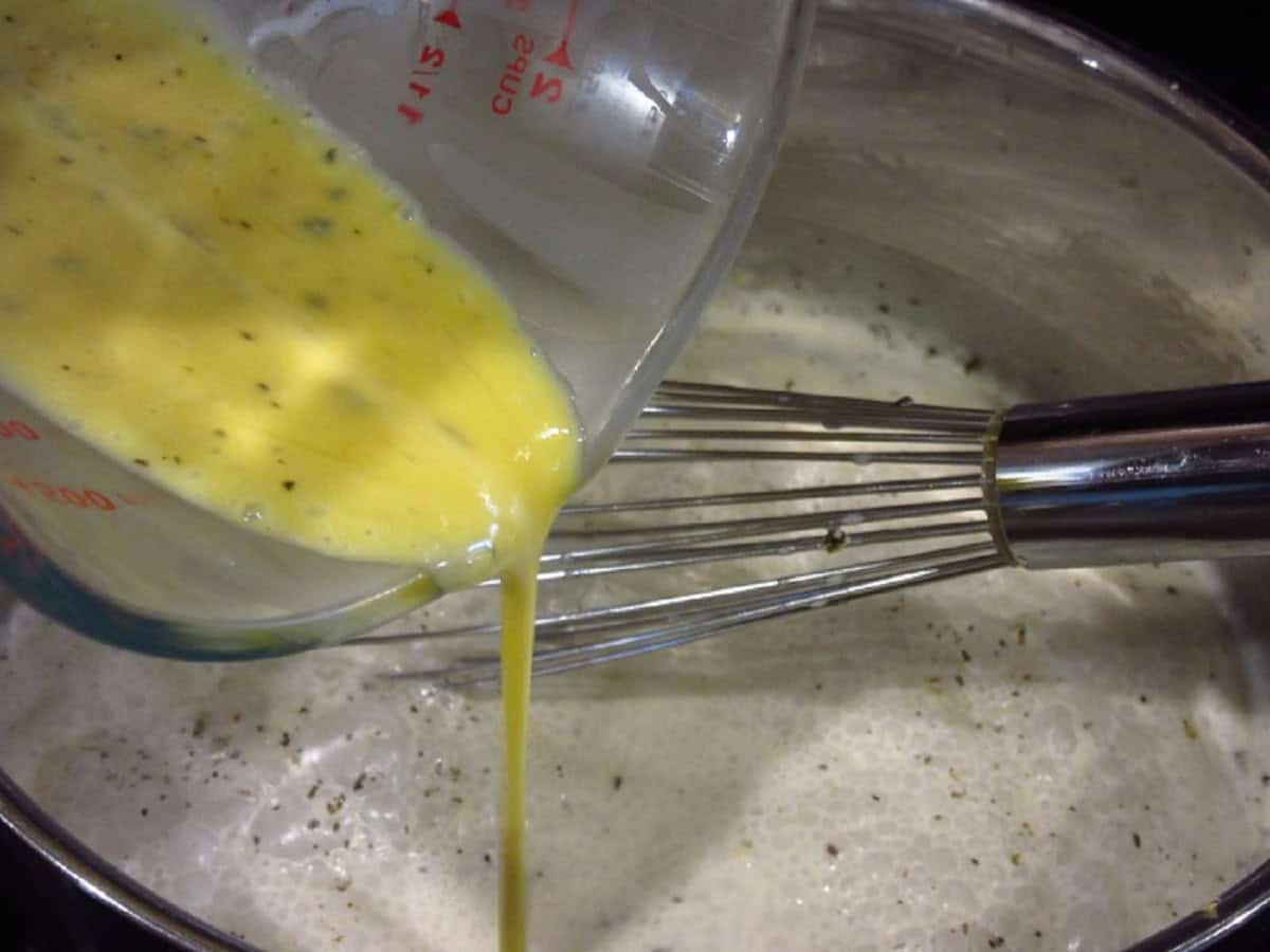Tempered egg being poured into a saucepan.