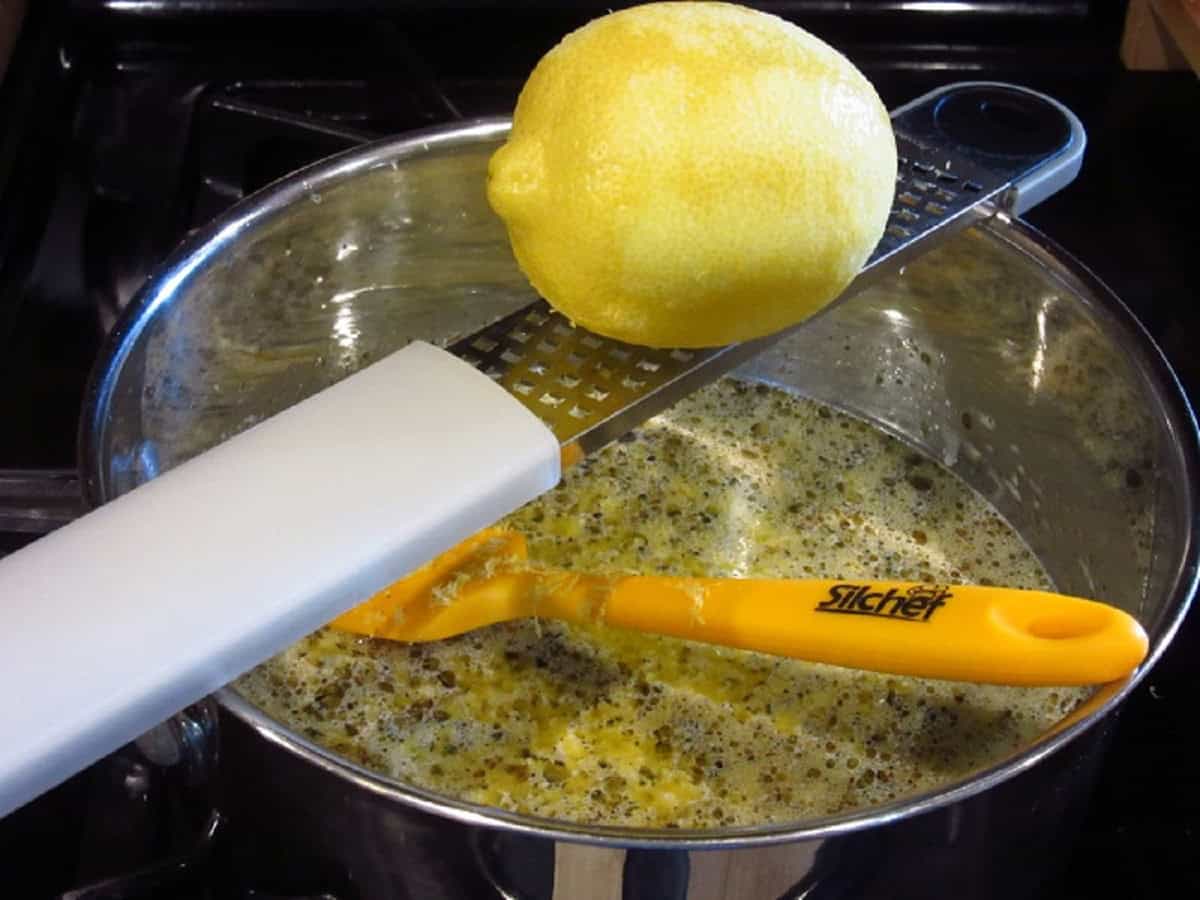 Fresh lemon zest being added to a saucepan.