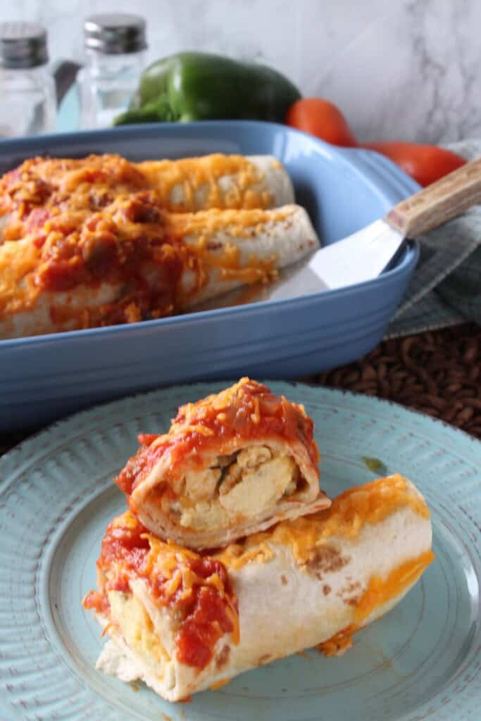 A air fryer breakfast burrito on a blue plate with a casserole dish in the background.