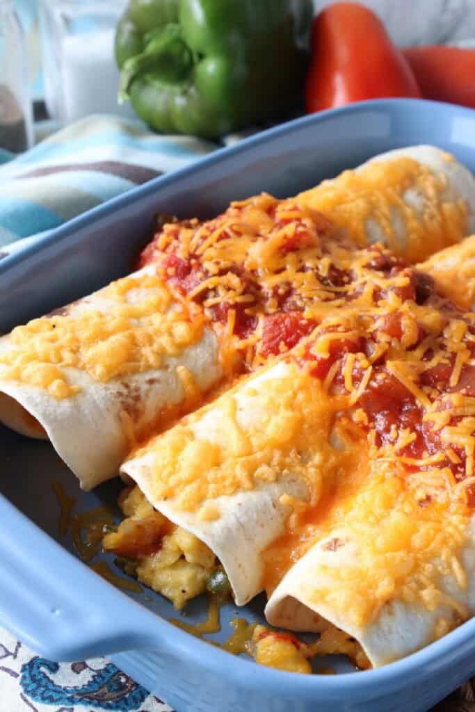 A blue casserole dish filled with three air fryer breakfast burritos.