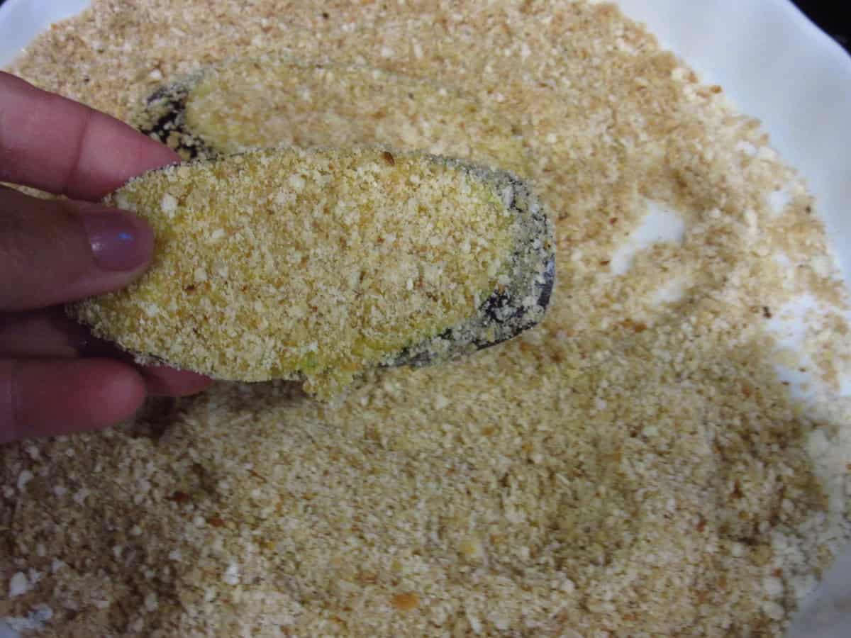 A cheese and breadcrumb coated eggplant slice before pan frying.