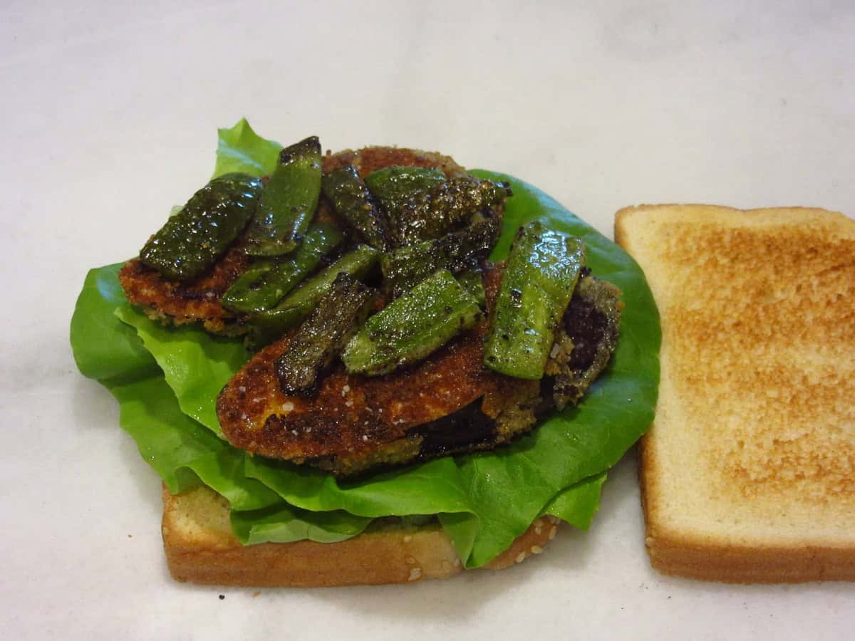 Green bell pepper slices on a sandwich with eggplant and lettuce.