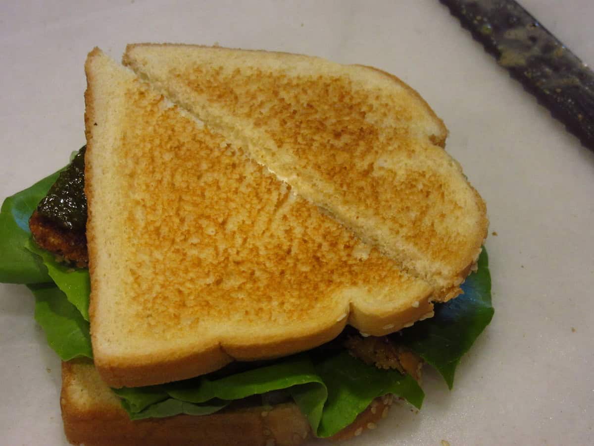 A fried eggplant sandwich on toast cut in half.