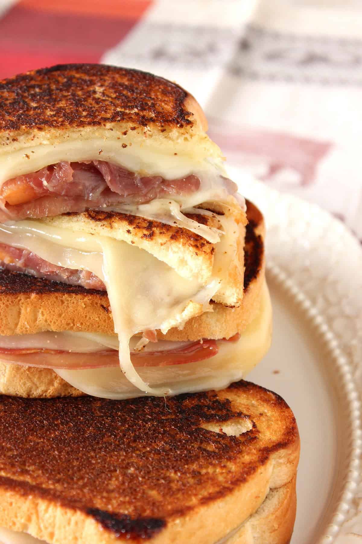 Delicious looking grilled cheese sandwiches with provolone, melon, and prosciutto on a pretty plate.