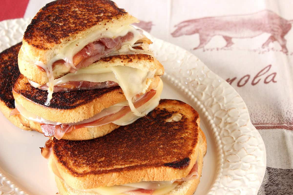 A pretty plate with grown up grilled cheese sandwiches with provolone and melon.