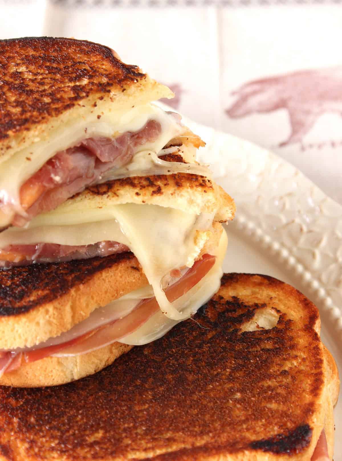 A stack of melted Provolone, Prosciutto, and Melon sandwiches.
