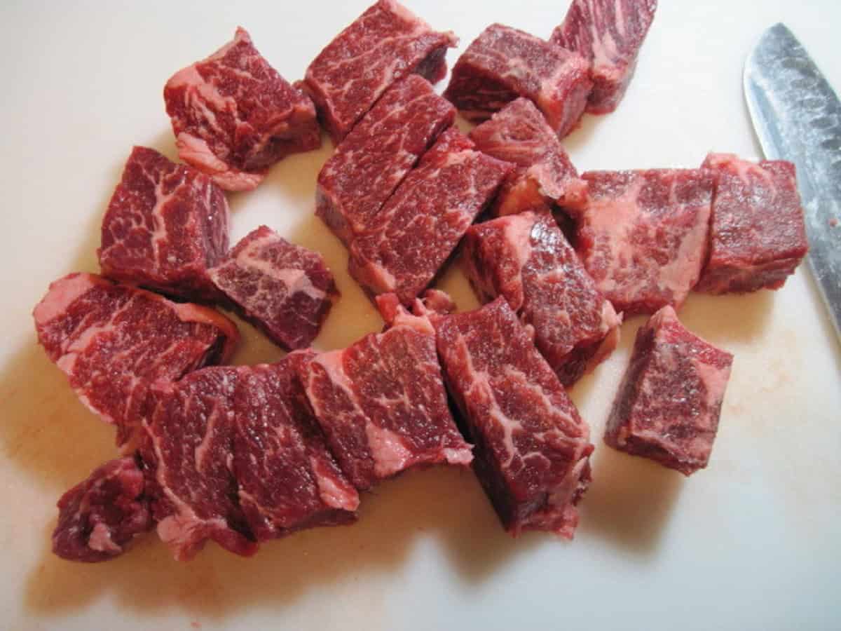 Cut up pieces of boneless beef short ribs on a cutting board.
