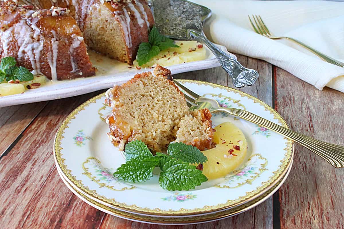 A slice of Hummingbird Cake on a pretty china plate with a sprig of mint.