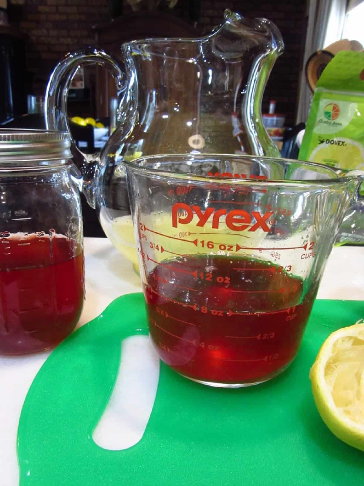 Strawberry simple syrup in a glass measuring cup.