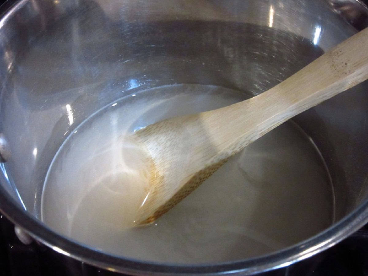 A wooden spoon in a saucepan making simple syrup.