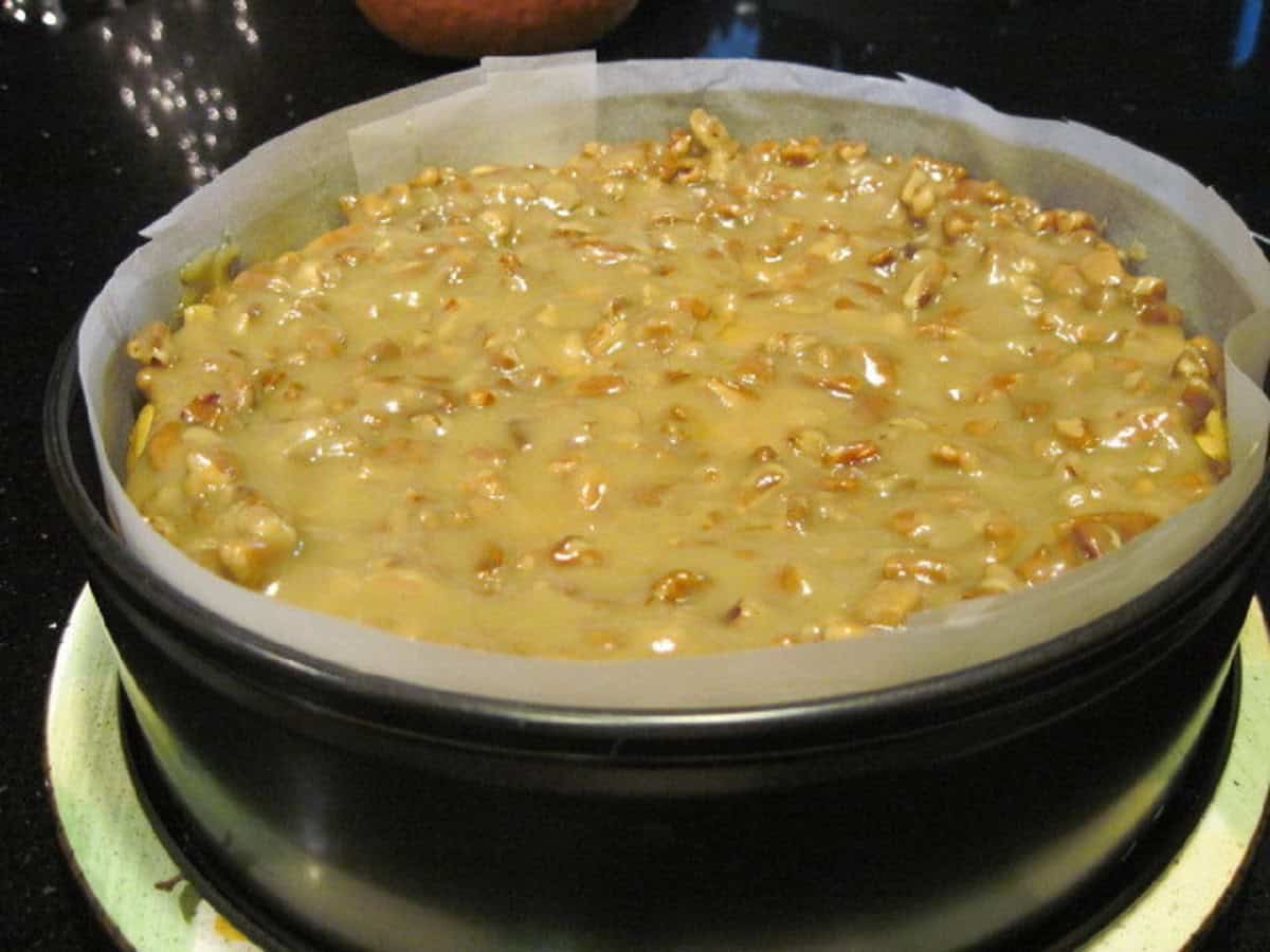 A glazed Maple Pecan Cheesecake in a springform pan and parchment paper.