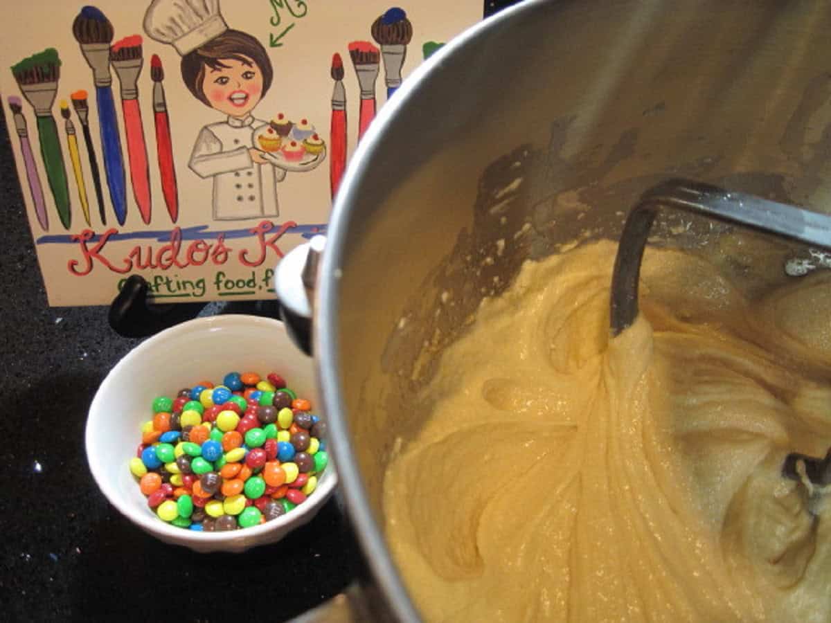 A small bowl of mini m and m's in a bowl next to cookie batter.