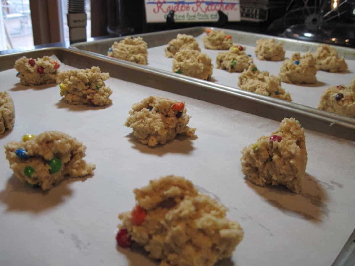 Scoops of mini m and m oatmeal cookie dough on baking sheets.