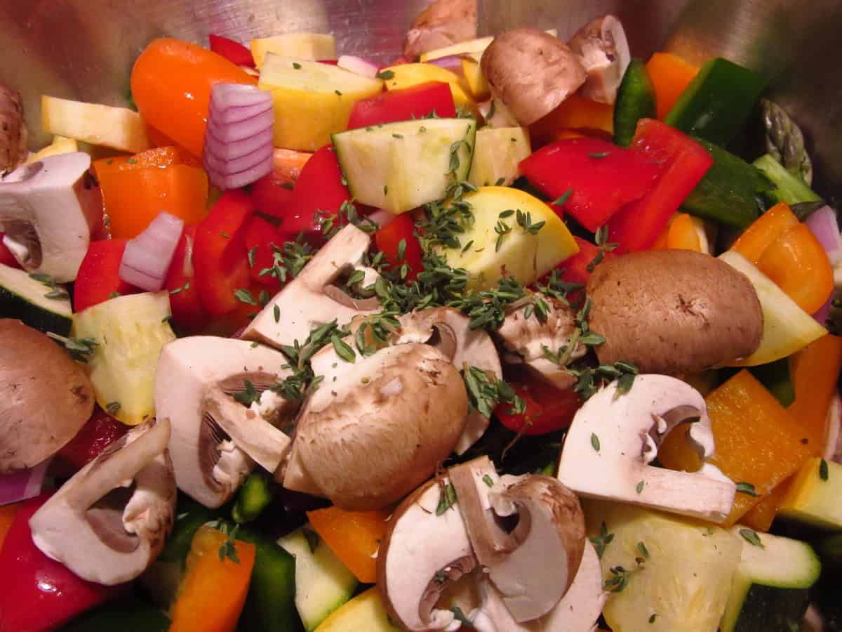 Fresh thyme leaves on top of chopped colorful rainbow vegetables.