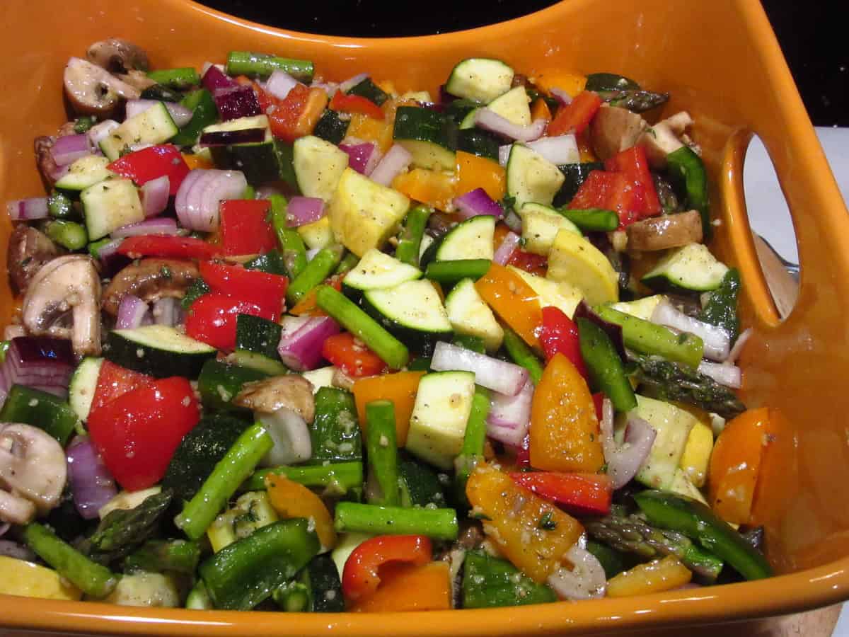 Beautiful chopped roasted rainbow vegetables in an orange casserole dish.