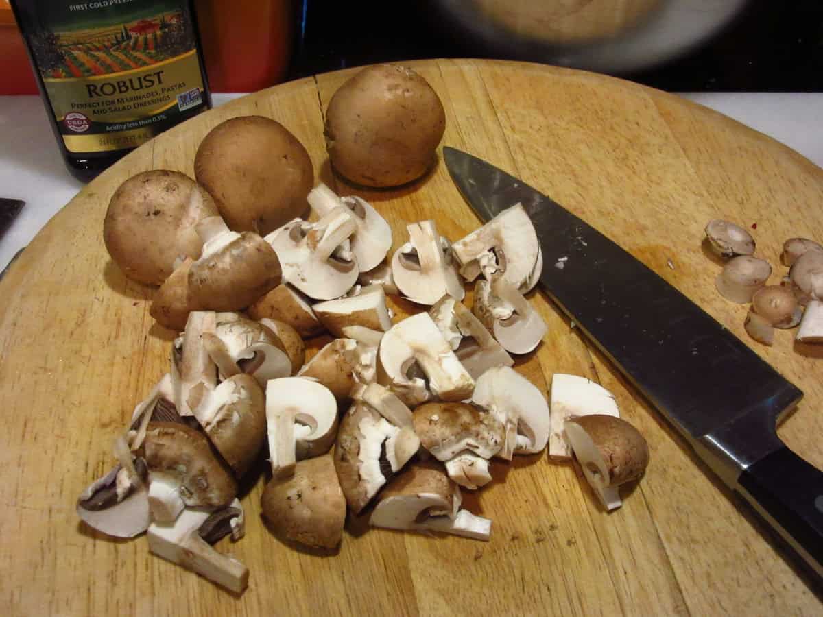Chopped cremini mushrooms on a cutting board.