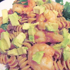 Rotini pasta with cooked shrimp and diced avocado on a plate.