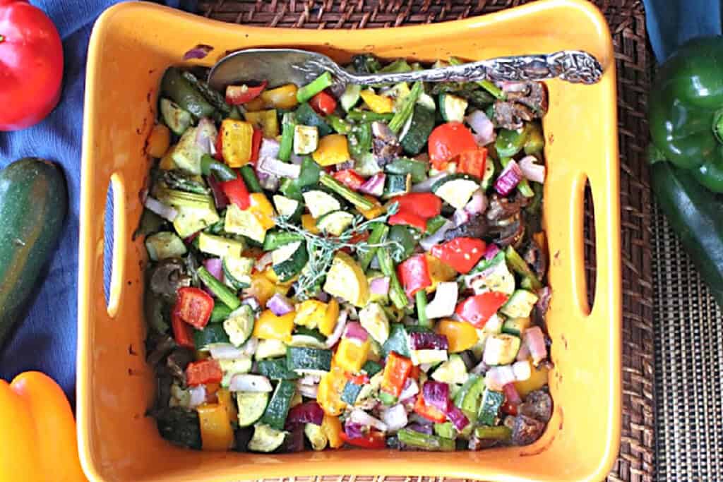 A orange oval casserole dish filled with Summertime's Roasted Rainbow Vegetables.