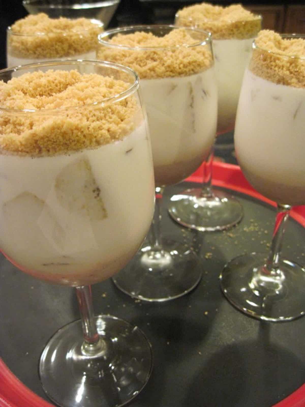 Five wine glasses filled with Banana Panna Cotta along with a crumble topping.
