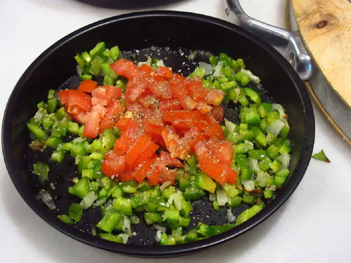 Tomato, pepper, and onion in a metal air fryer pan.