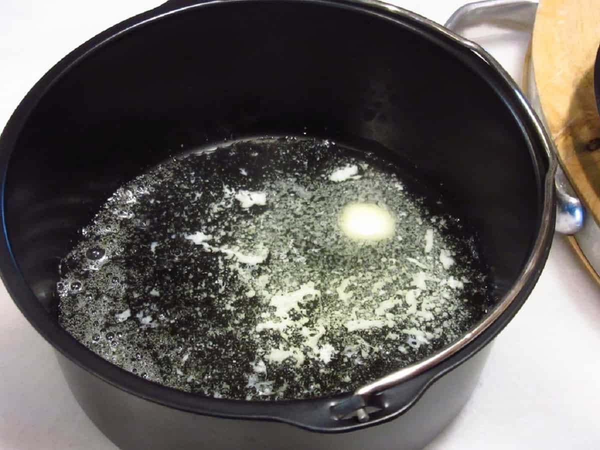 Melted butter in a dark metal air fryer pan.