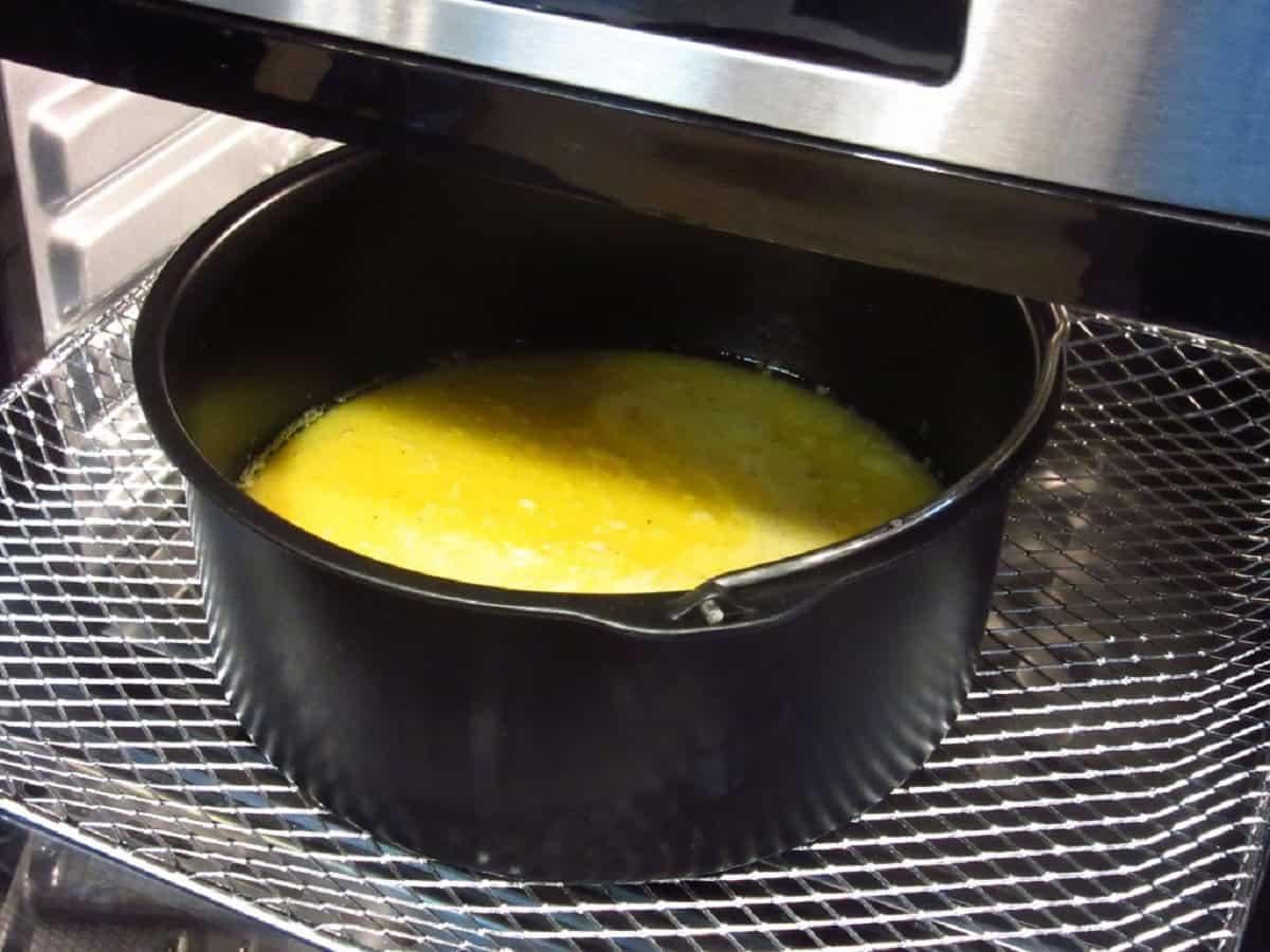 A round metal pan with eggs in an air fryer.