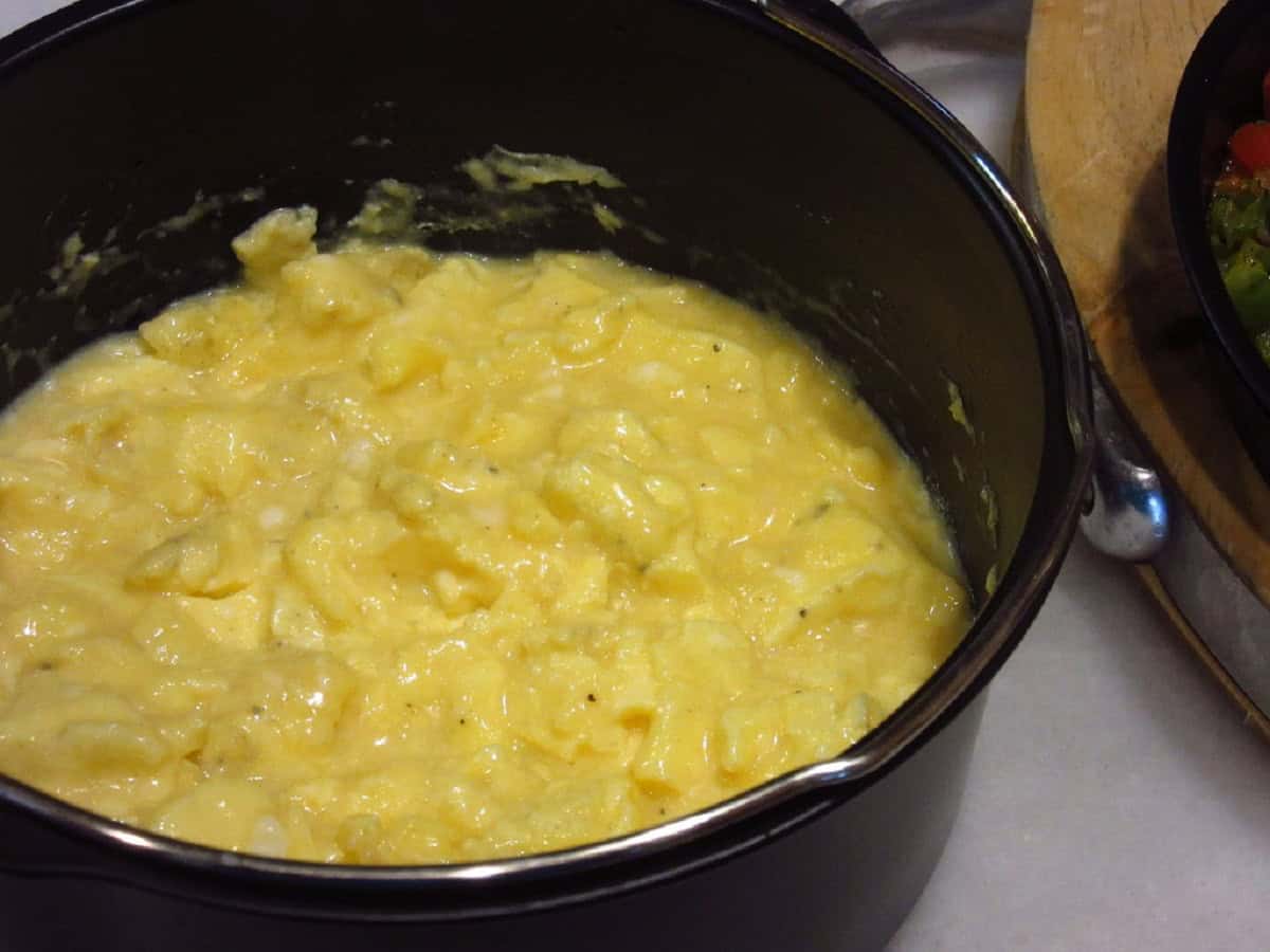 Scrambled eggs in a round metal air fryer pan.