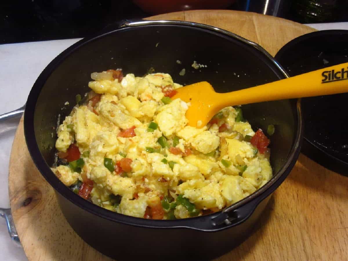 Scrambled eggs mixed with peppers and onions in an air fryer pan.