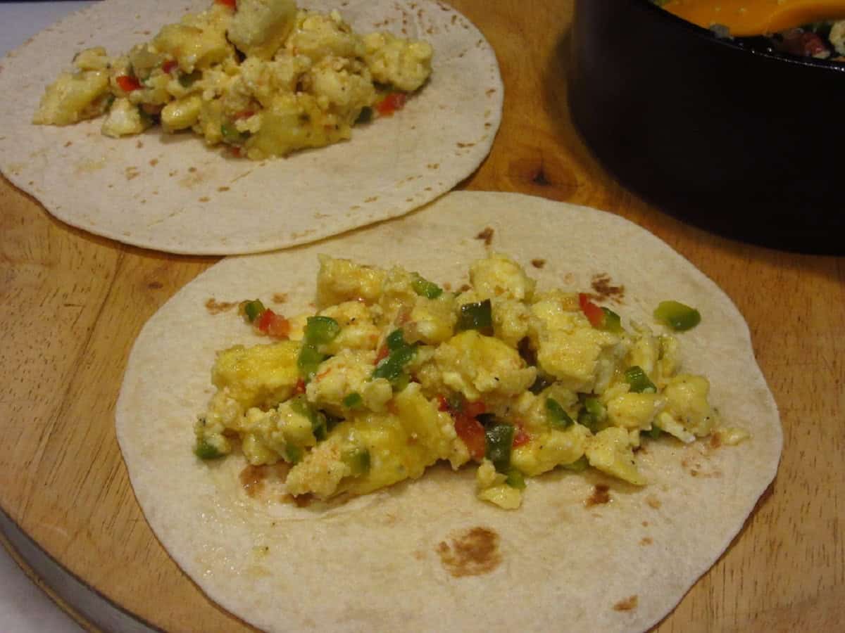 Scrambled eggs with peppers and onions on top of flour tortillas.