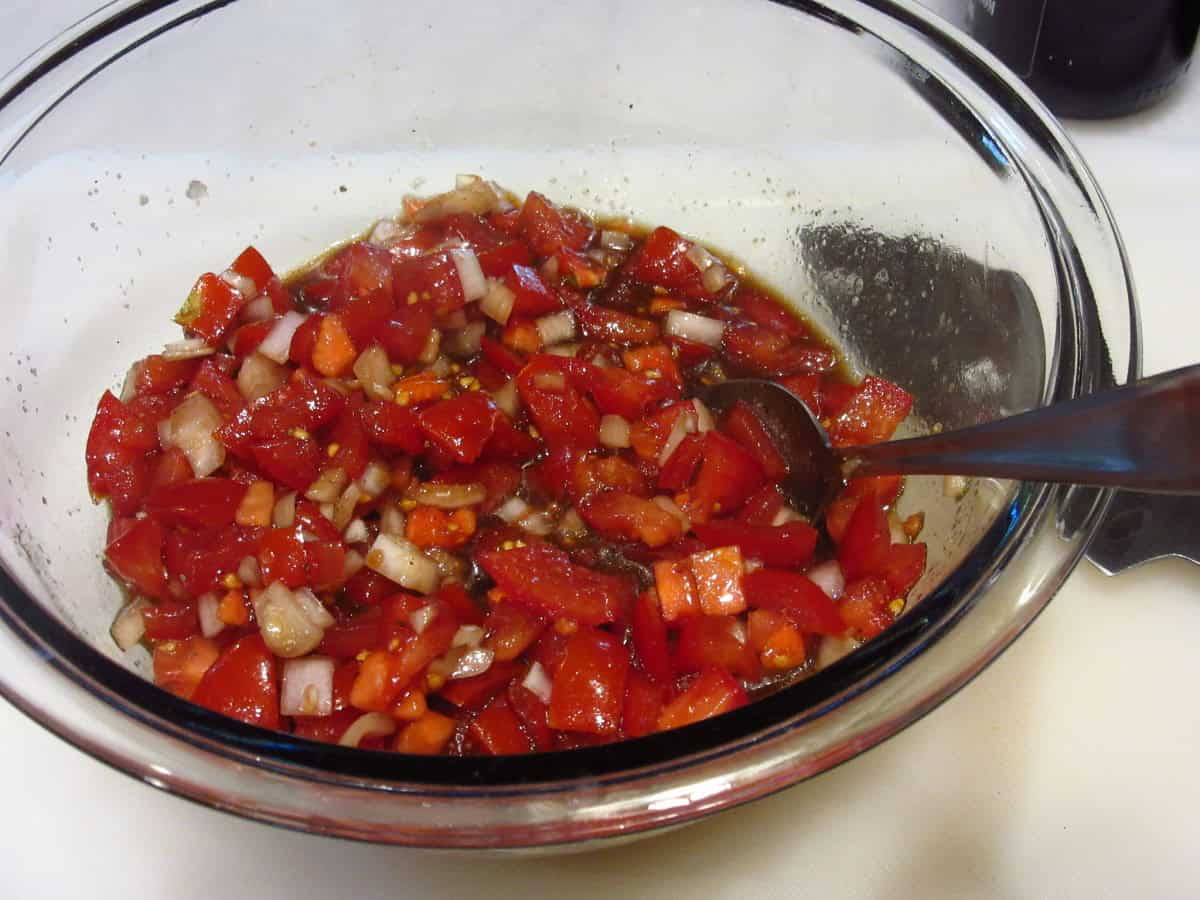 A glass bowl filled with tomatoes and shallots.