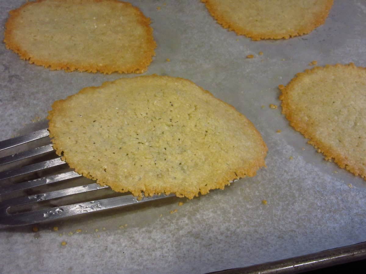 A spatula lifting a Parmesan crisp from a baking sheet.