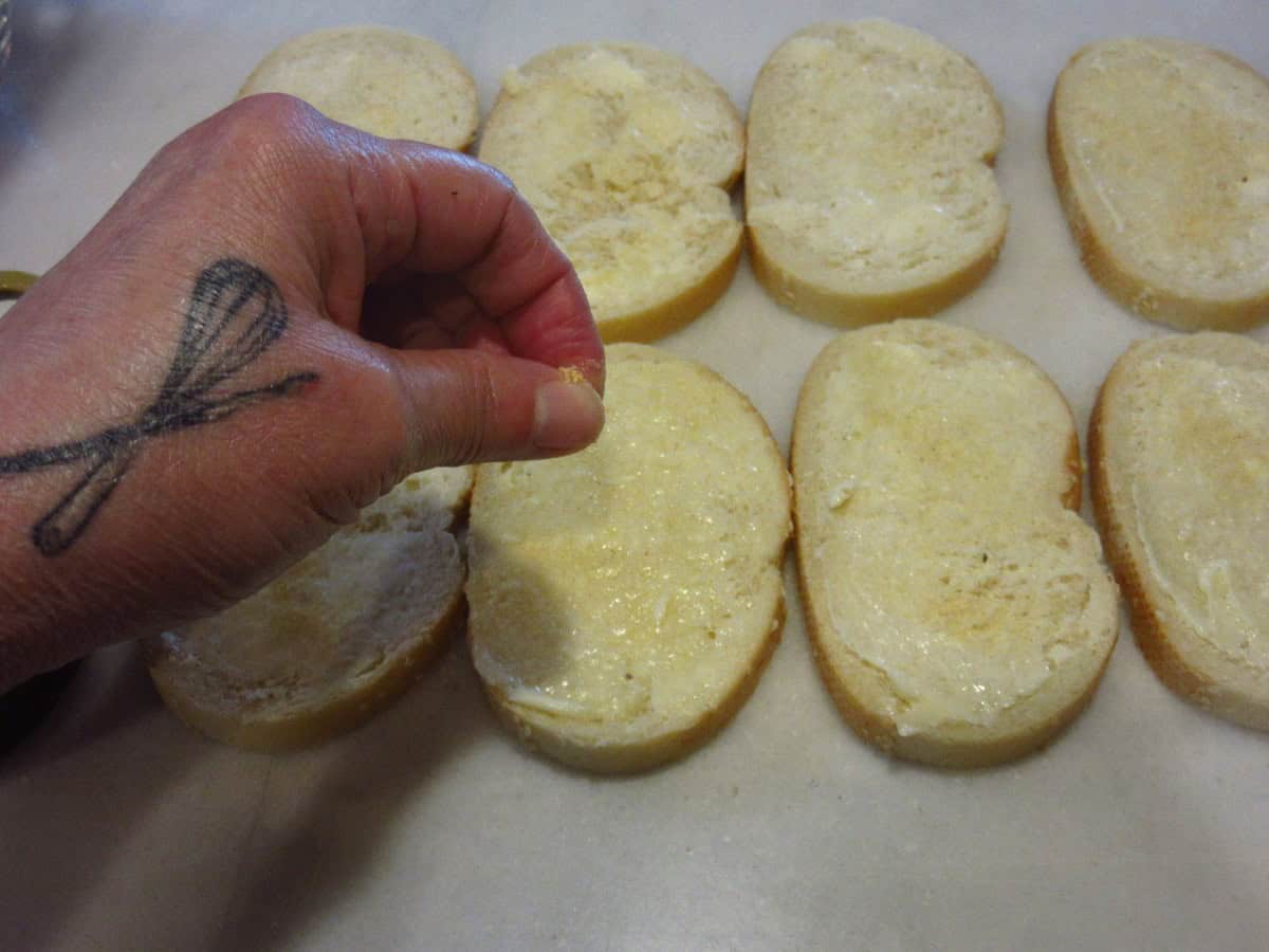 Garlic powder being sprinkled on bread.