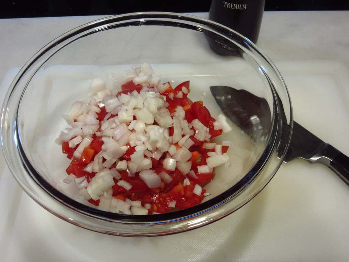 Diced tomatoes and shallots in a glass bowl.