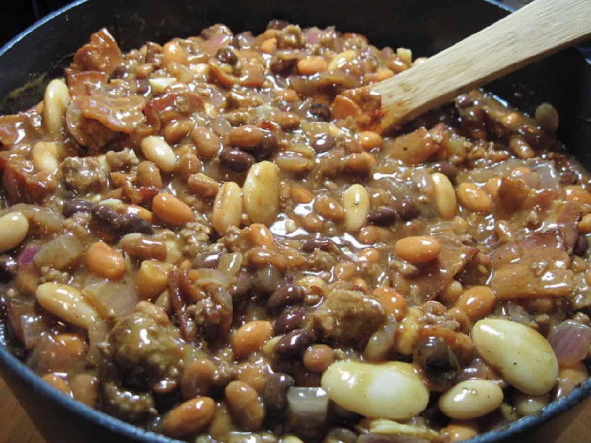 Calico beans in a pot with a wooden spoon.