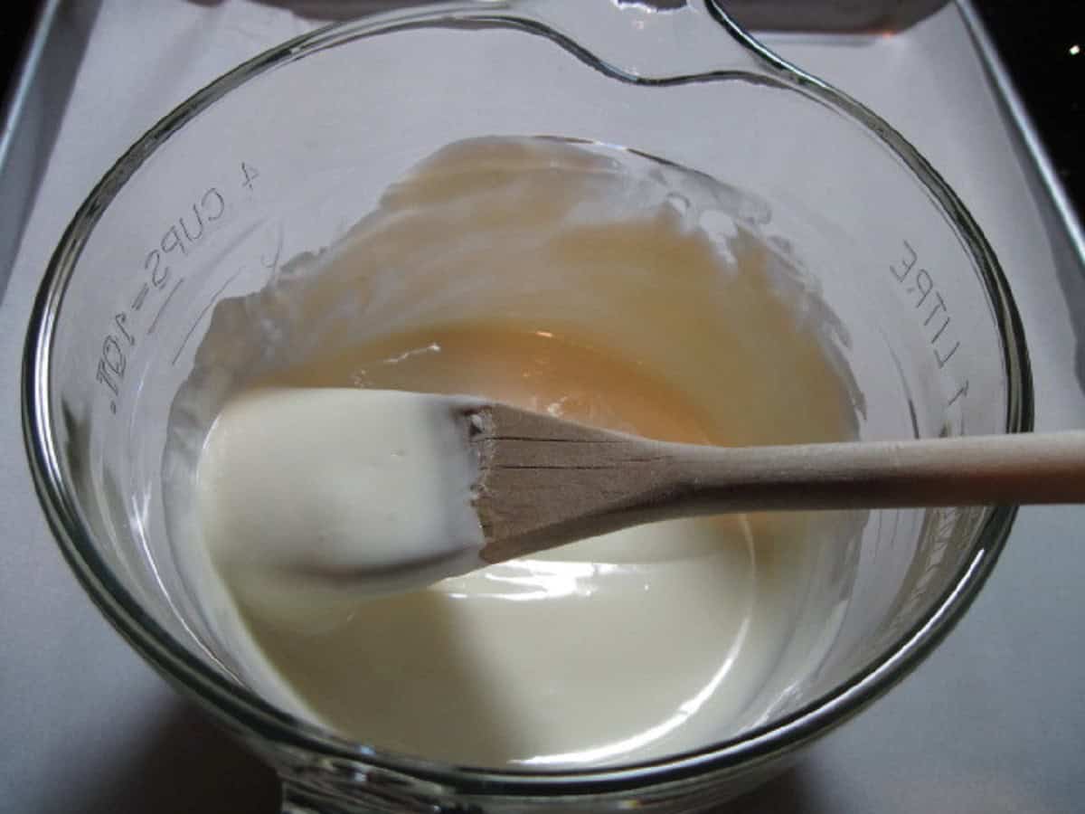 A wooden spoon in a bowl of melted white chocolate.